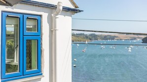 A white building with blue-framed windows overlooking a body of water with boats. - 2 Bed in Helford (oc-hcview) (Helford)