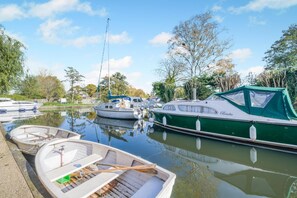 Ein ruhiges Gewässer mit mehreren vertäuten Booten, darunter ein grünes Boot namens 'Bridie' und ein kleineres Ruderboot.