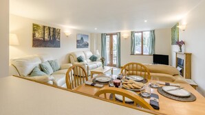 Una sala de estar con sofá, sillas, una mesa de comedor para dos personas y televisión.