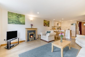 A living room with a fireplace, a television, a sofa, and a dining area with chairs. - 2 Bed in Smallburgh (oc-c33736) (Low Street)