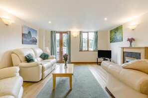Ein Wohnzimmer mit zwei Sofas, einem Couchtisch, einem Fernseher und einem Kamin.