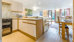 A compact kitchen with a stove, oven, and a dining area with a table and chairs. - 2 Bed in Smallburgh (oc-g33735) (Low Street)