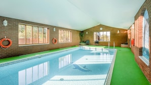 An indoor swimming pool with a green floor, brick walls, and windows. - 2 Bed in Smallburgh (oc-g33735) (Low Street)