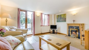 A living room with a sofa, a TV, a fireplace, and a painting on the wall. - 2 Bed in Smallburgh (oc-g33735) (Low Street)