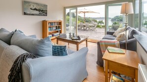 Een moderne woonkamer met een bank, salontafel, boekenkast en uitzicht op de omgeving.