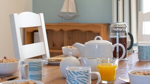 A breakfast table with bowls of cereal, a teapot, a coffee pot, a glass of orange juice, and a slice of toast. - 3 Bed in Trimingham (oc-2290) (Trimingham)