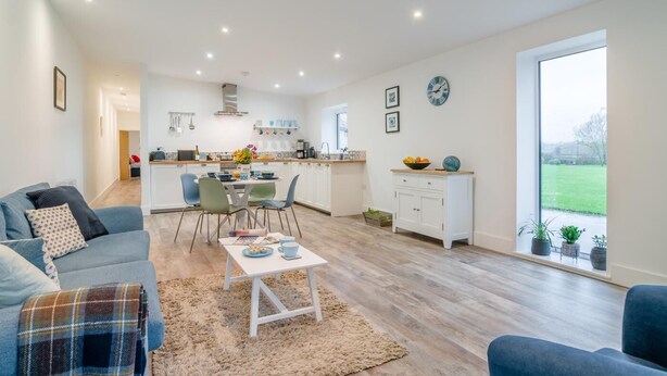 A modern living room with a sofa, a coffee table, and a dining area with chairs and a table. - 2 Bed in Hinton Blewett (oc-g34070) (Hinton Blewett)