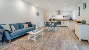 A modern living room with a sofa, coffee table, and dining area. - 2 Bed in Hinton Blewett (oc-g34070) (Hinton Blewett)