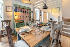 A wooden dining table set with plates, bowls, and wine glasses, surrounded by rustic chairs. - 3 Bed in Helford (oc-hccott) (Helford)