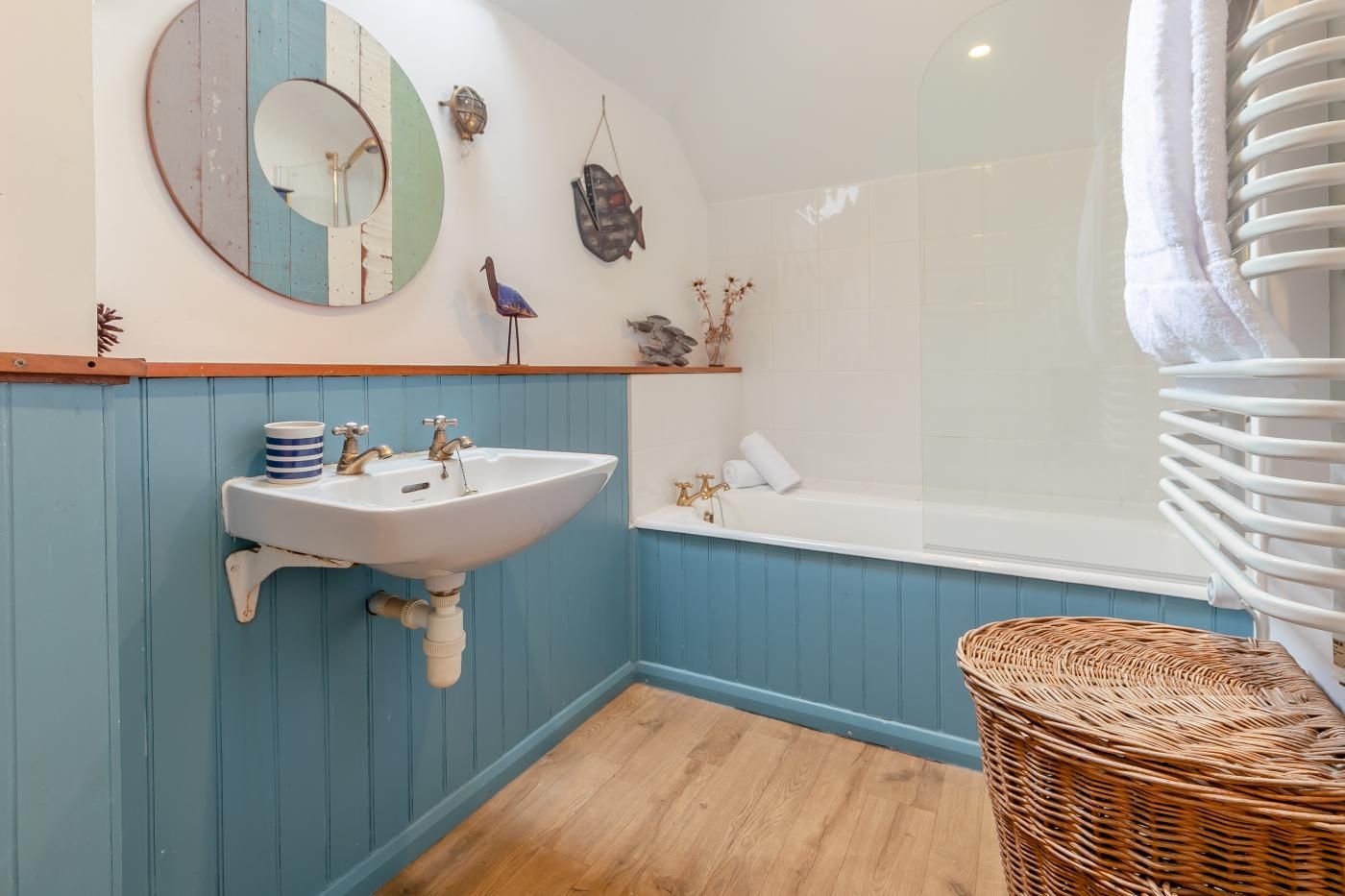 A bathroom with a white sink, a bathtub, and a wicker chair.