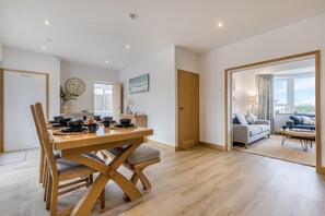 Ein modernes Wohnzimmer mit einem Holzesstisch, einer Couch und Blick ins Freie.