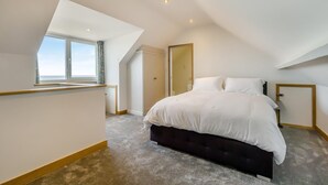 A bedroom with a large bed, a window, and a door. - 4 Bed in Cromer (oc-b34005) (Cromer)