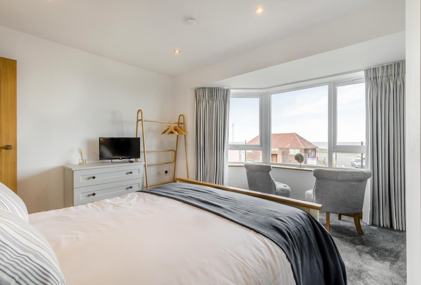A modern hotel room with a bed, a TV, a desk, and a chair.