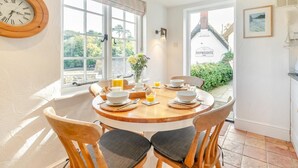 A dining area with a round wooden table, six chairs, and breakfast items. - 2 Bed in Helford (oc-hcpopi) (Helford)