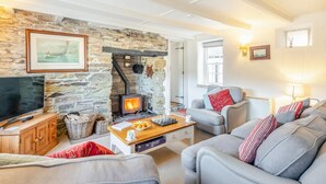 A cozy living room with a stone wall, a fireplace, a television, and comfortable seating. - 2 Bed in Helford (oc-hcpopi) (Helford)