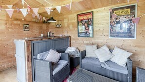 Ein gemütliches Blockhaus-Interieur mit Barbereich, Korbmöbeln und Filmplakaten an den Wänden.