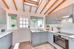 A modern kitchen with grey cabinets, a built-in oven, and a window with a view of greenery. - 2 Bed in Dartmouth (oc-sd84ab) (Dartmouth)