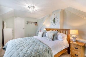 Una camera da letto con un letto, un comodino, una lampada e una decorazione a forma di cuore sulla parete.