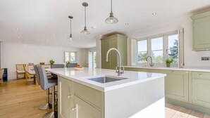 A modern kitchen with a central island, pendant lighting, and a view to the outside. - 5 Bed in Walberswick (oc-hlwal) (Walberswick)