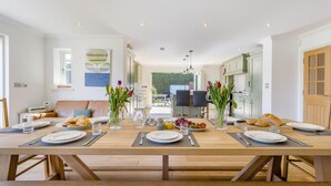 A dining area with a long wooden table set for a meal, surrounded by chairs. - 5 Bed in Walberswick (oc-hlwal) (Walberswick)