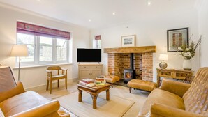 A living room with a fireplace, a television, and leather furniture. - 5 Bed in Walberswick (oc-hlwal) (Walberswick)