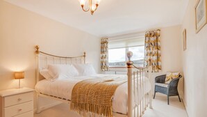 A bedroom with a bed, bedside table, lamp, chair, window with curtains, and a view of the outside. - 3 Bed in Rothbury (oc-nb1976) (Rothbury)