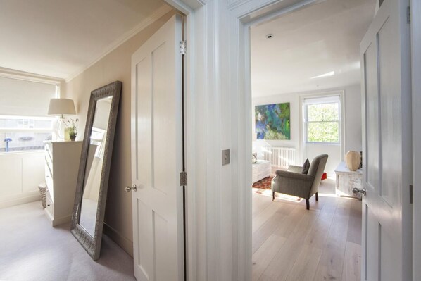 A hallway leading to a living room with a large mirror, a sofa, and a painting on the wall. - 1 Bed in Bath (oc-bhr48) (Bath)