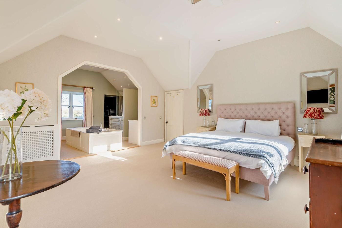 Een ruime slaapkamer met een groot bed, een kaptafel en een inloopkast.