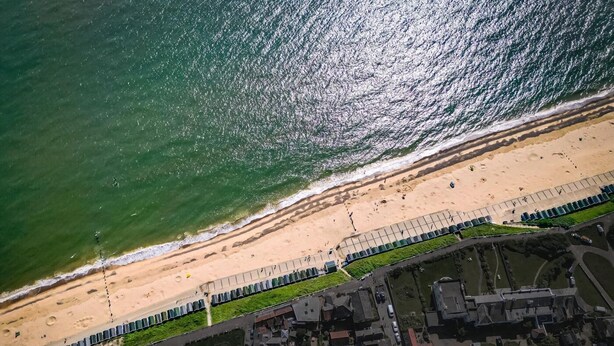 Vista aérea de una zona costera con playa, paseo marítimo y edificios residenciales.