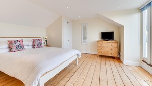 Un dormitorio con cama, cómoda, televisor y ventana.