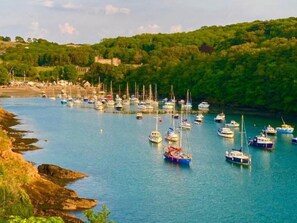 Un port où de nombreux bateaux sont amarrés, entouré d’une végétation luxuriante et bordé d’une colline sur laquelle se trouve un bâtiment.