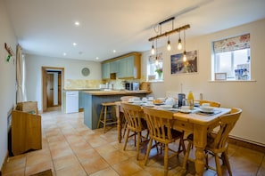 A kitchen with a dining area, wooden chairs, a kitchen island, and a window with curtains.