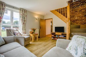 Ein Wohnzimmer mit Fernseher, einer Holztreppe und Blick ins Freie.