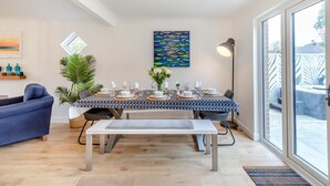 A dining area with a table set for four, a blue sofa, a potted plant, and a painting on the wall. - 4 Bed in Freshwater (oc-s33684) (Freshwater)