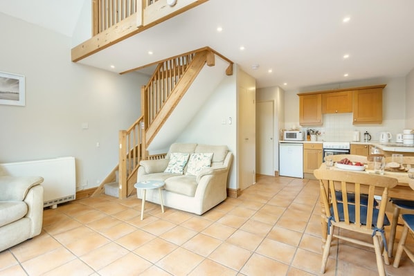 A modern kitchen with wooden cabinets, a dining table, and a built-in oven. - 1 Bed in Snape (oc-fcf) (Snape)