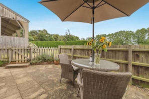 A patio with wicker furniture, a table, and an umbrella.