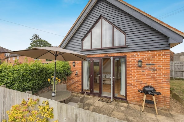 A house with a brick exterior, a large glass door, and a patio with a table and umbrella.