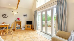 A spacious living area with a dining table, a sofa, a TV, and a bookshelf. - 1 Bed in Snape (oc-fcf) (Snape)