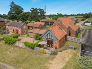 A residential area with brick houses, a wooden fence, and a gravel driveway. - 1 Bed in Snape (oc-fcf) (Snape)