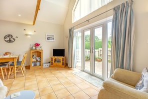 A spacious living area with a dining table, a sofa, a TV, and a bookshelf.