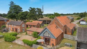 A residential area with brick houses, a wooden fence, and a gravel driveway. - 1 Bed in Snape (oc-fcf) (Snape)