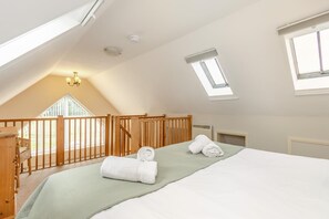 A bedroom with a sloped ceiling, a wooden railing, a bed with white linens, and a skylight. - 1 Bed in Snape (oc-fcf) (Snape)