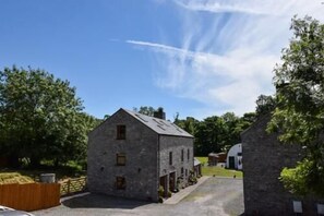 A stone building with a gabled roof, a small porch, and a paved driveway. - 3 Bed in Pembroke (oc-25585) (Pembroke)
