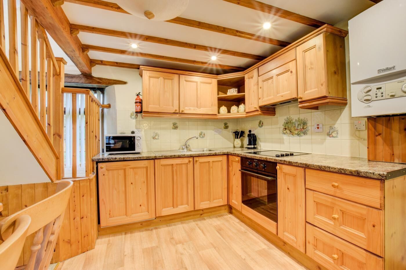 A wooden kitchen with a built-in oven, microwave, and a Vaillant refrigerator.