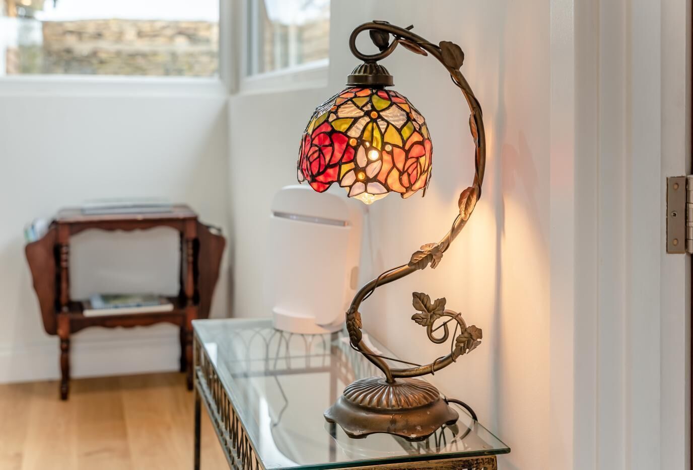 A stained glass lamp on a glass table near a window.