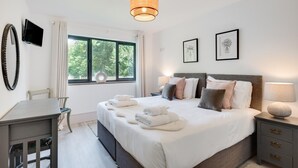 Una camera d'albergo con un letto, comodini, una scrivania, una sedia, una finestra con vista e una televisione.