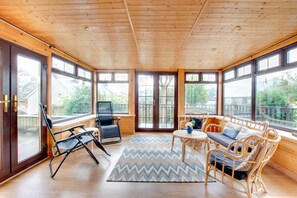 A sunlit room with large windows, a wooden ceiling, wicker furniture, and a patterned rug. - 3 Bed in Saundersfoot (oc-pw9096) (Saundersfoot)