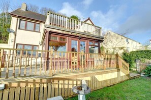 A two-story house with a wooden deck, a balcony, and a satellite dish. - 3 Bed in Saundersfoot (oc-pw9096) (Saundersfoot)