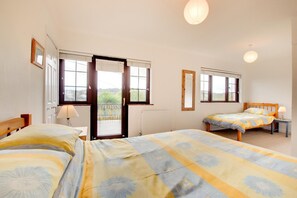 Une chambre avec deux lits, une fenêtre, une porte et une table de chevet.