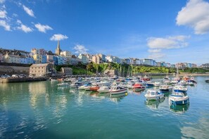 A harbor with numerous boats docked, a church spire, and colorful buildings along the waterfront. - 3 Bed in Saundersfoot (oc-pw9096) (Saundersfoot)